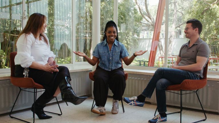 Three people are sitting in chairs facing each other